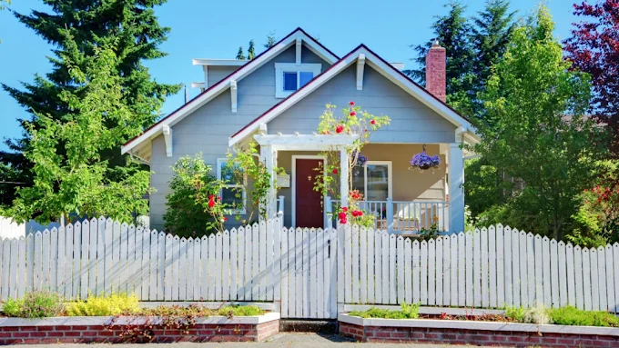 Freshly painted craftsman cottage with white picket fence