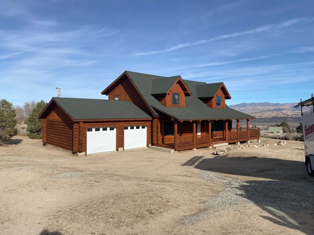 Stained log ranch home with green metal roof and wraparound porch