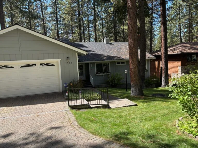 Sage-green ranch home freshly painted under tall pines