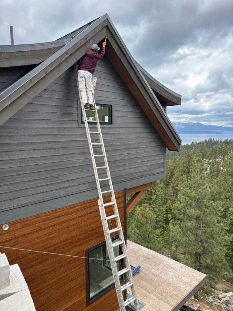 Painter on a ladder repainting a Lake Tahoe hillside home